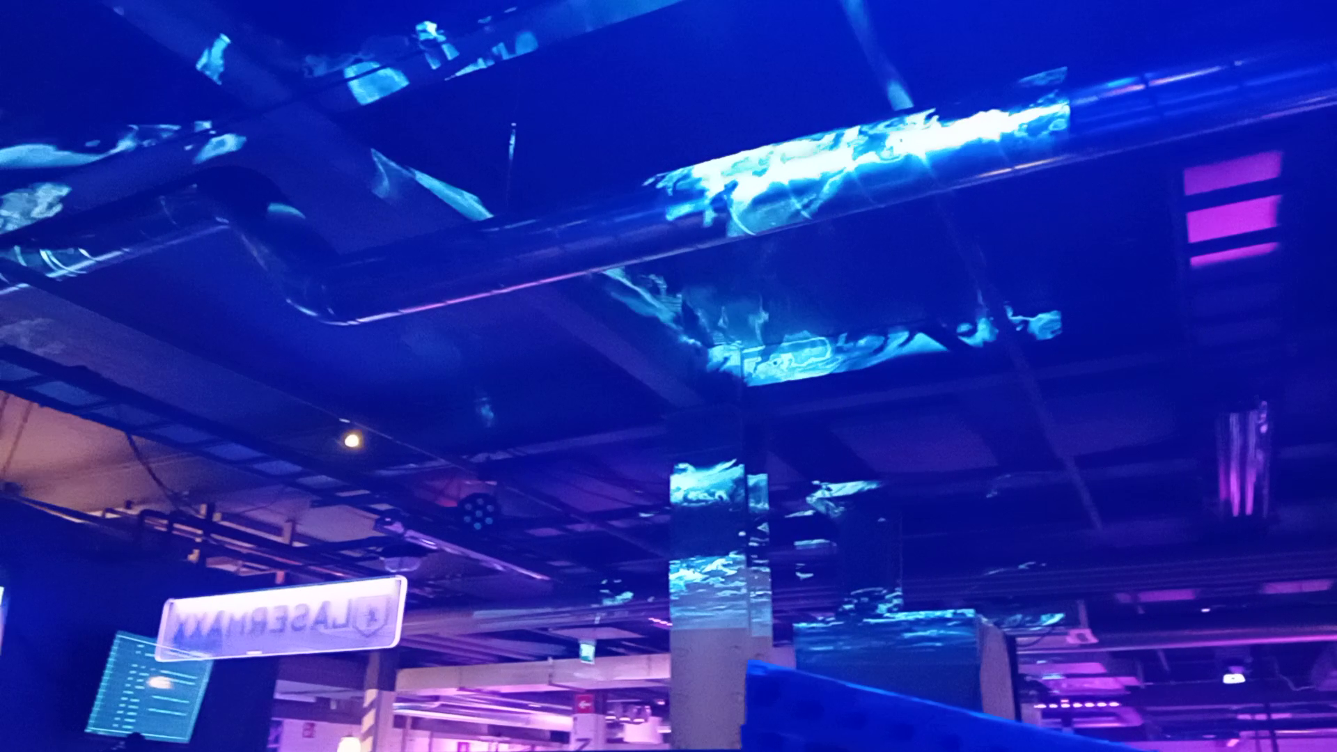 Industrial pillars and pipes at a venue with glowing distorted clouds patterns projection mapped onto them, like the sky over the industrial ceiling